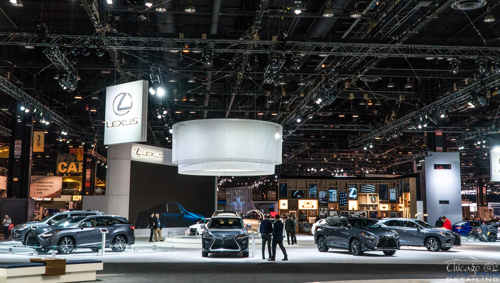 A group of people are standing in front of a display of cars at a car show.