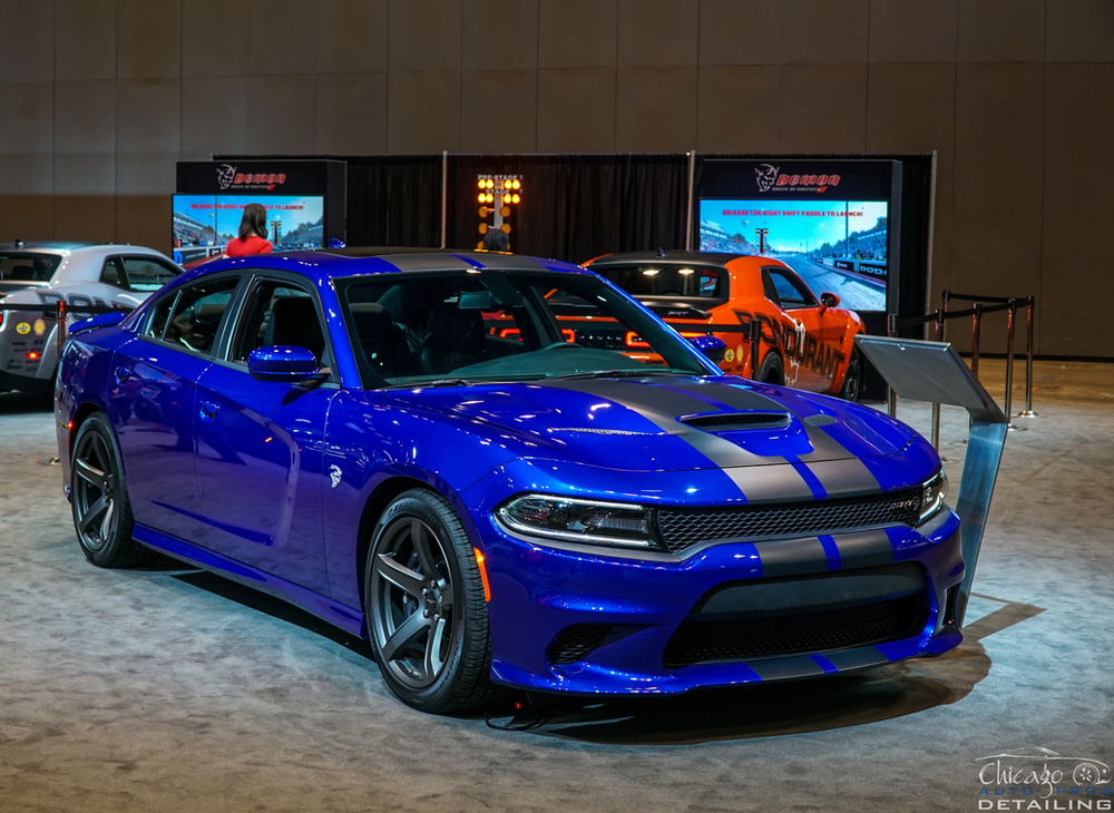 A blue dodge charger is on display at a car show.