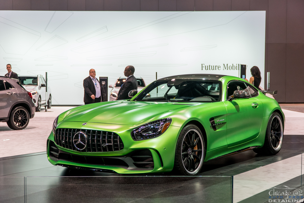 A green mercedes amg gt r is on display at a car show.