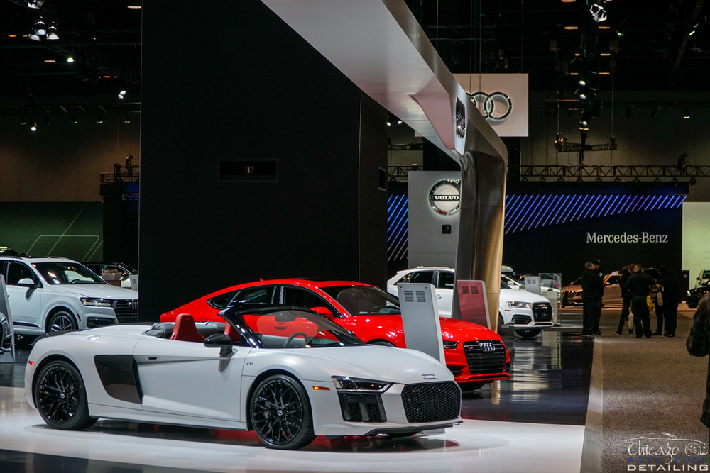 A white audi r8 convertible is on display at a car show