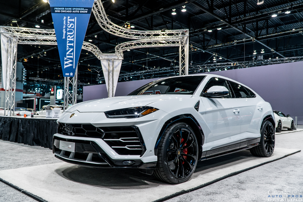 A white lamborghini urus is on display at a car show.