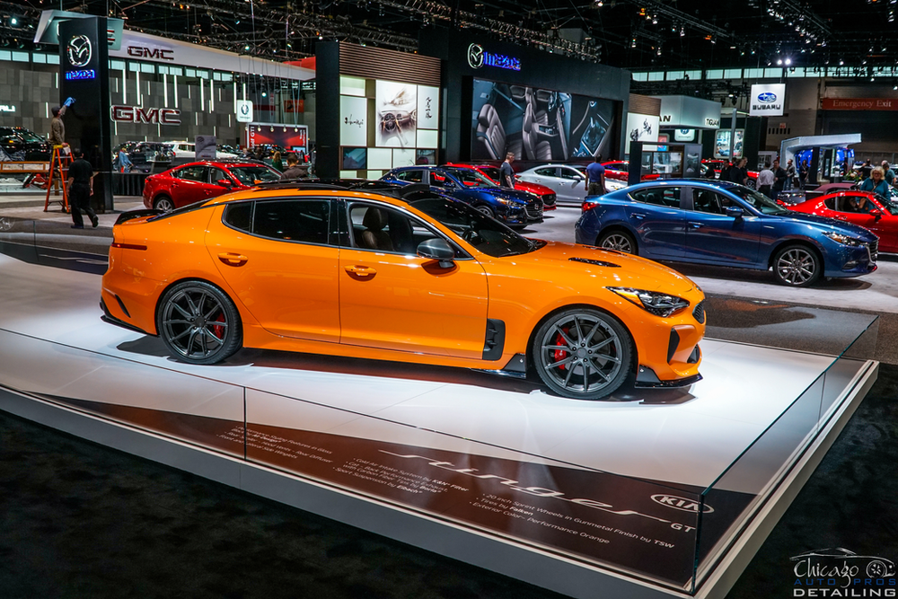 A yellow car is on display at a car show.