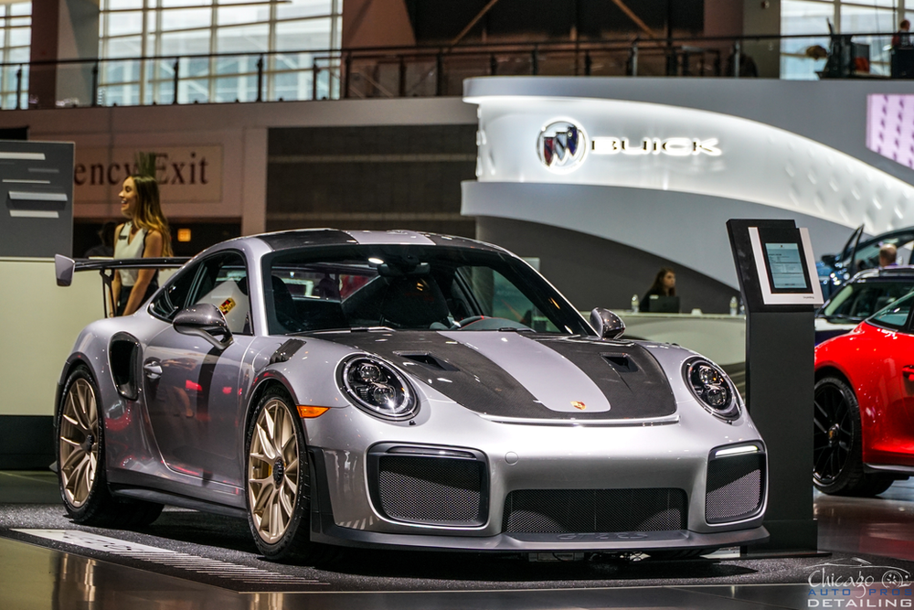 A silver porsche 911 gt2 rs is on display at a car show.