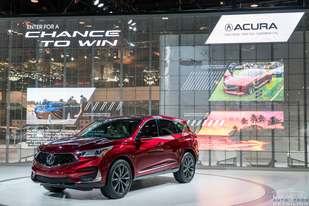 A red acura is on display at a car show.