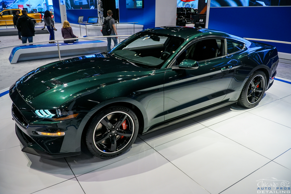 A green ford mustang is on display at a car show.