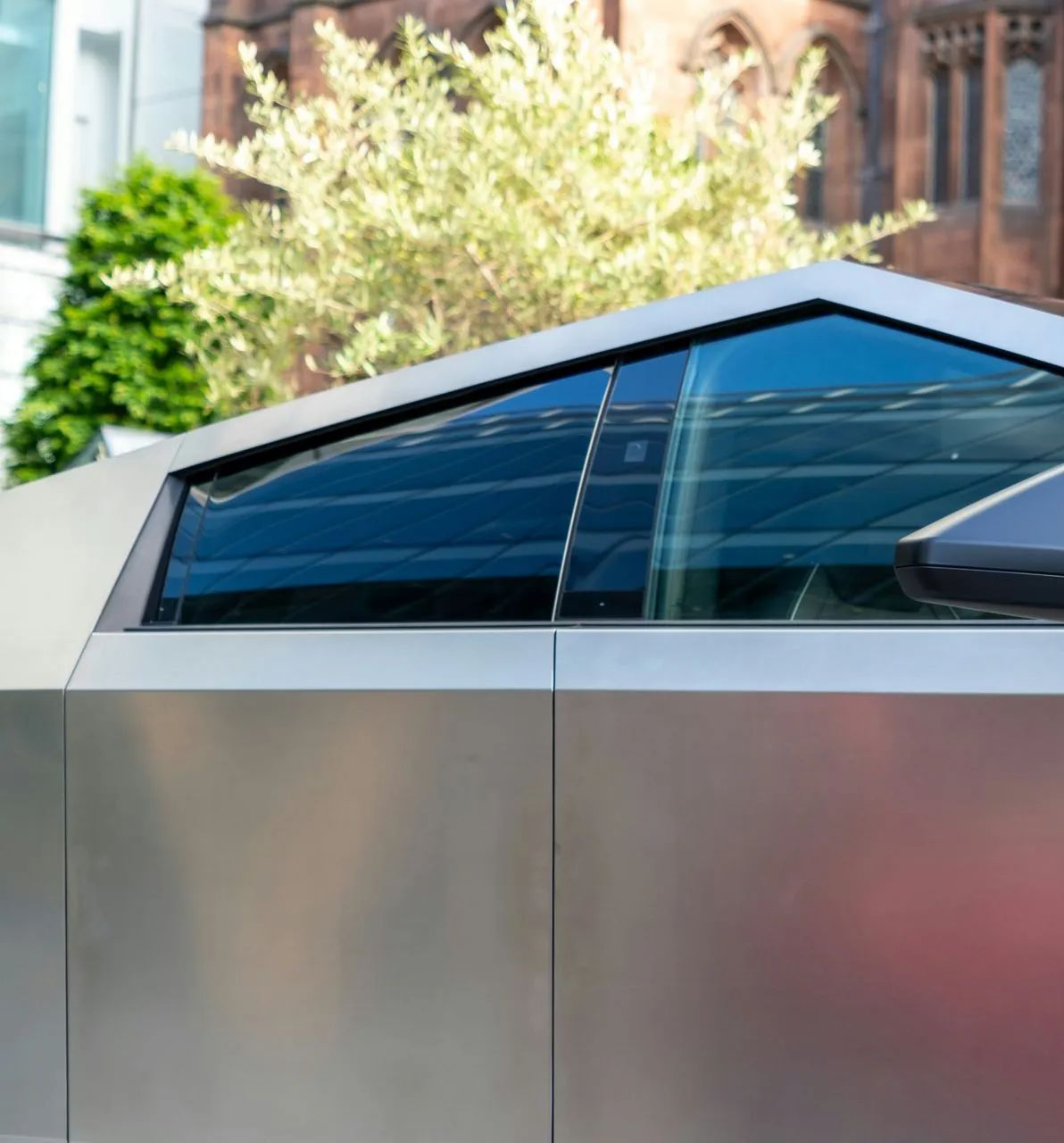 A close up of a tesla cybertruck parked in front of a building.