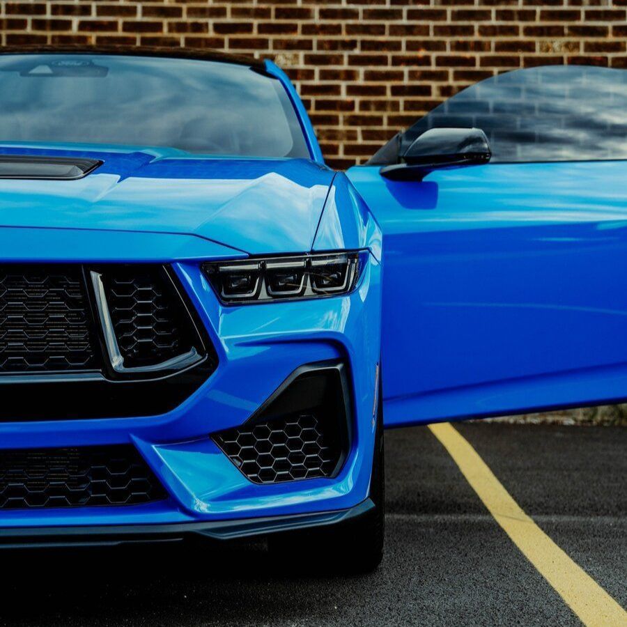 A blue sports car is parked in a parking lot with its doors open.