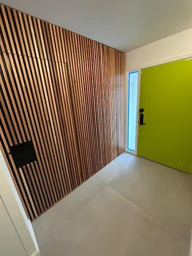 Wooden slatted wall with a lime green door and a small window next to it.