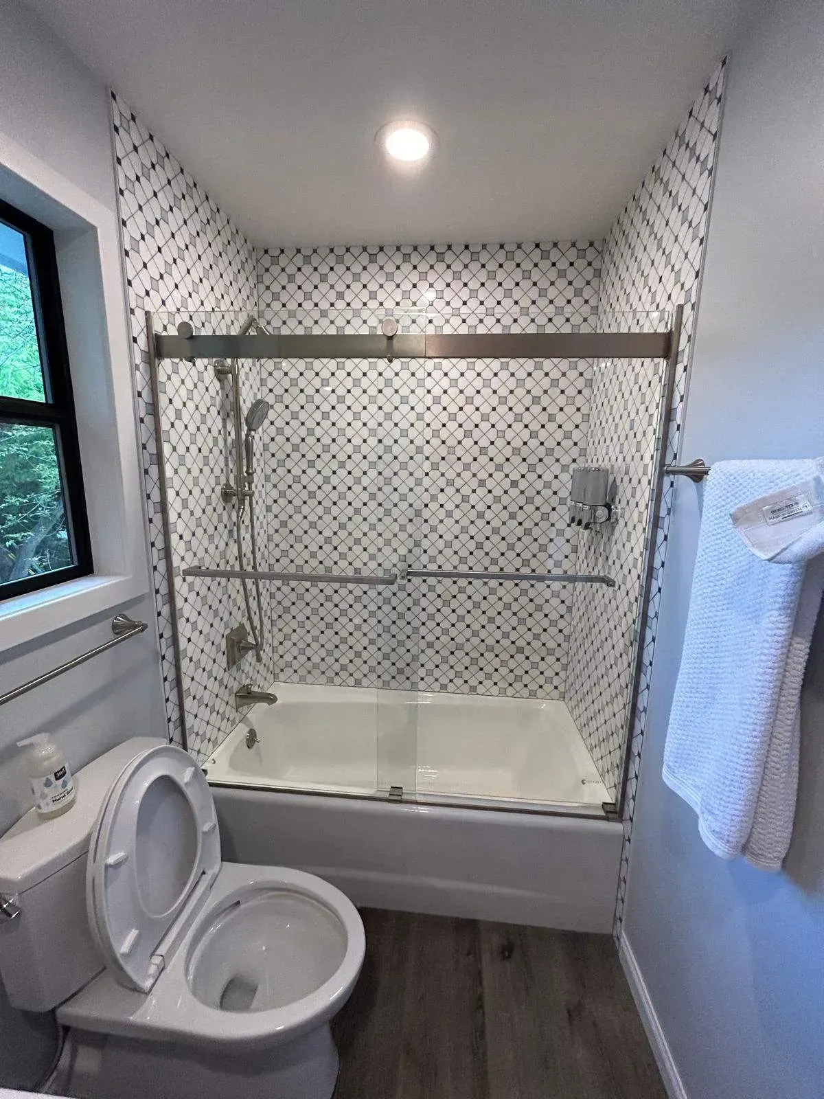 Bathroom with white tile shower, toilet, and gray walls.