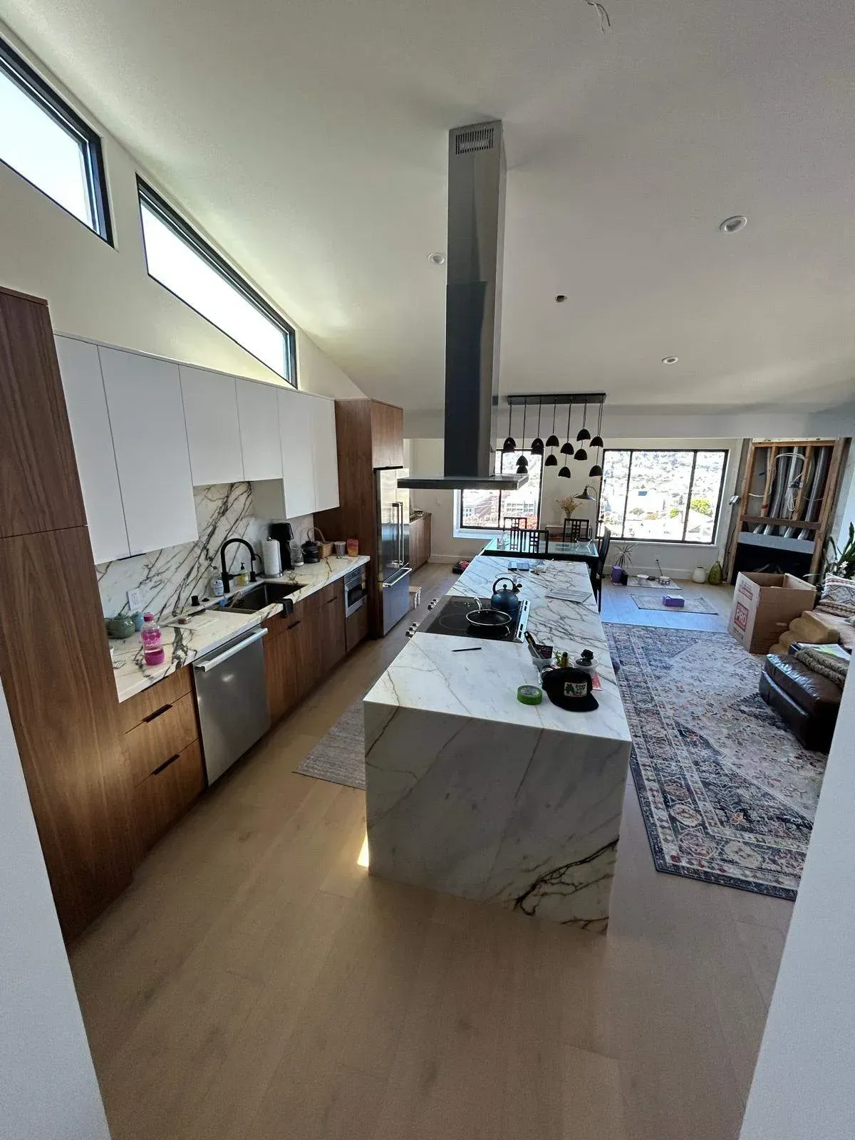 Modern kitchen with white and wood cabinets, marble island, and stainless steel appliances.