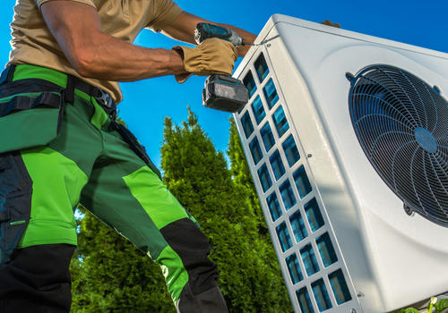 view of technician from below as he screws in a side panel into a new heat pump installation