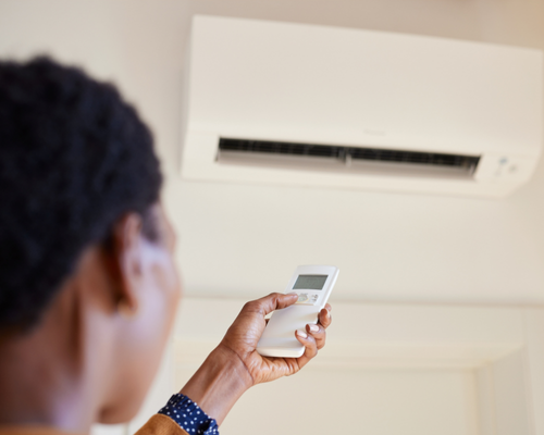 a homeowner points a remote at a mini split heat pump in a Littleton, co home