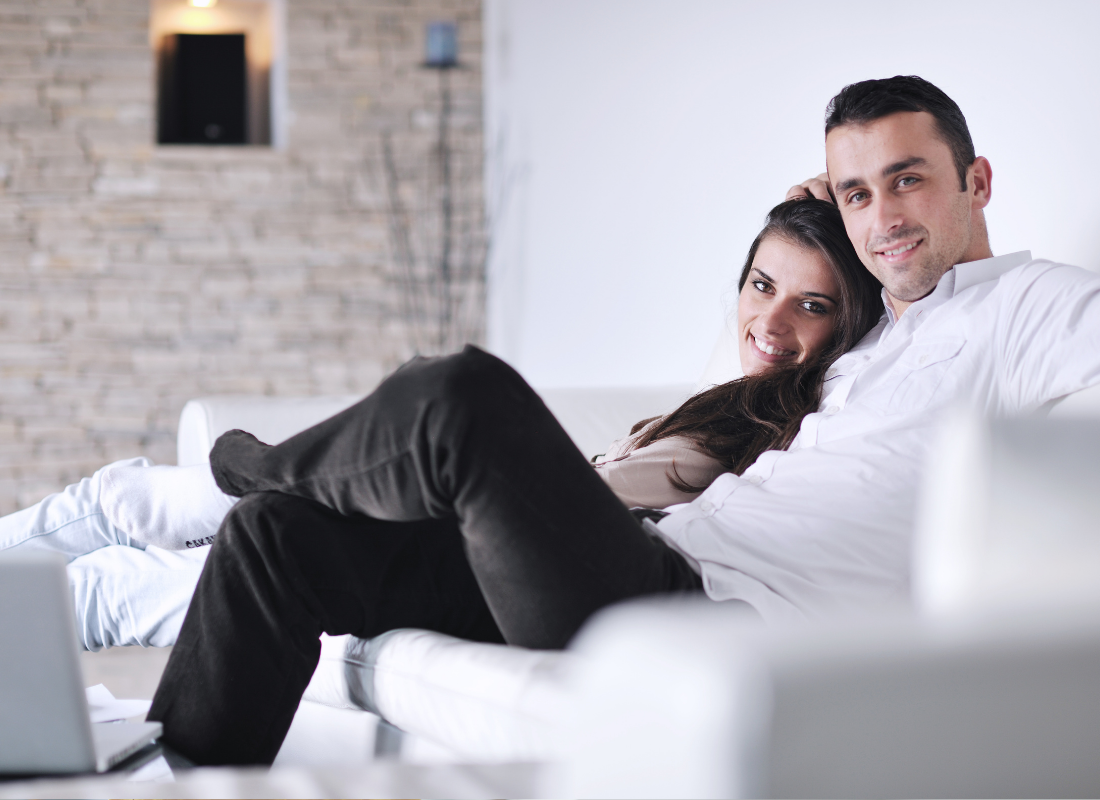 A couple cuddles on the couch in a comfortable looking home