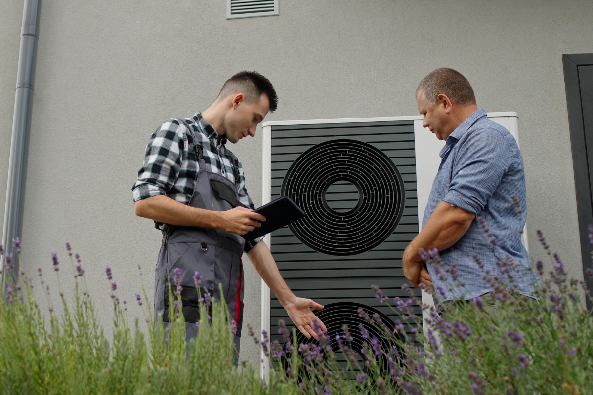 Denver heat pump technician going over the features of a new heat pump unit with the homeowner outside of a home