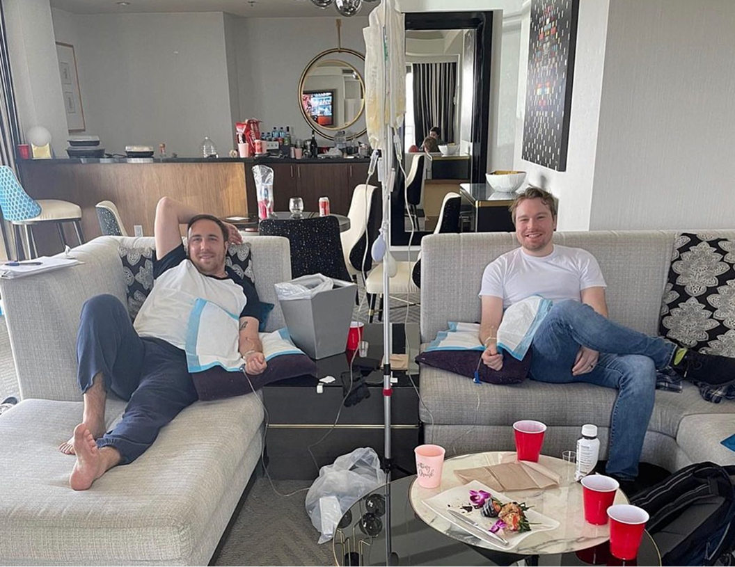 Two people are sitting on a couch in a living room.