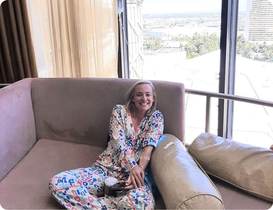 A woman is sitting on a couch in front of a large window.