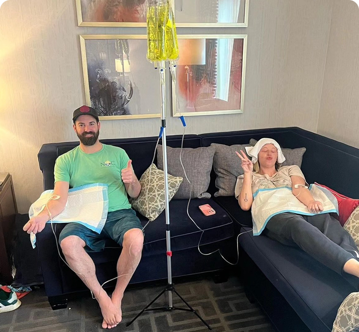A man and a woman are sitting on a couch with iv drips.