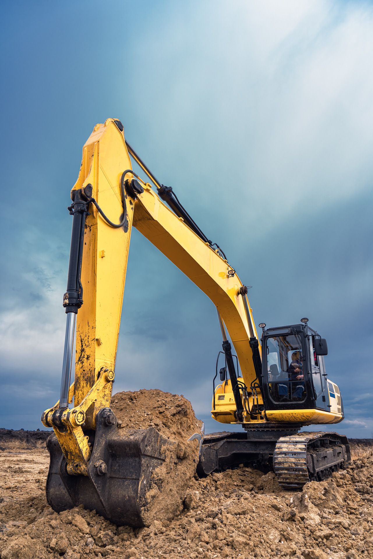 A yellow excavator is digging a hole in the dirt