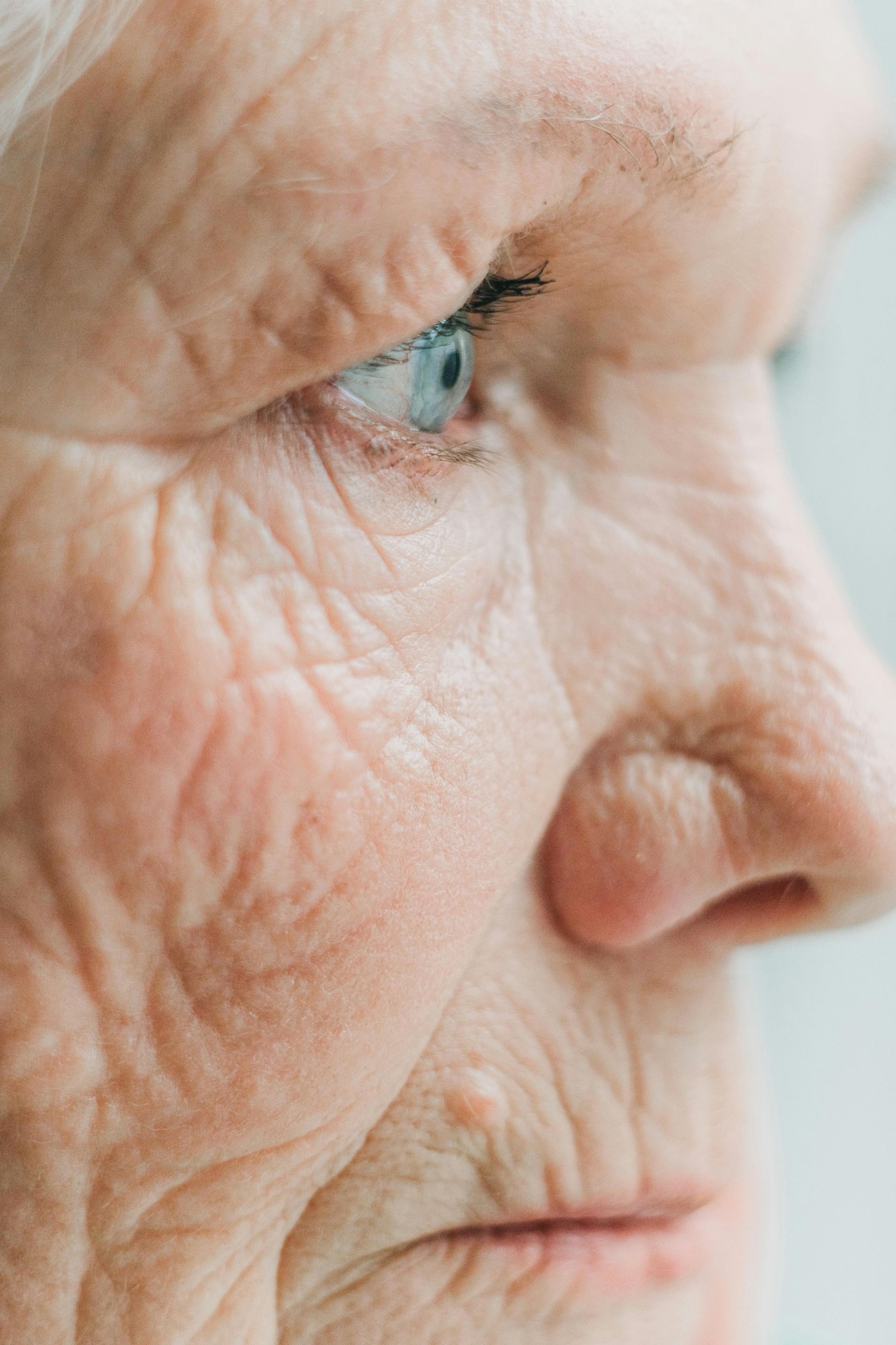 Close-up of a person's face looking up. Brown eyes with mascara, thick, shaped eyebrows, and fair skin.