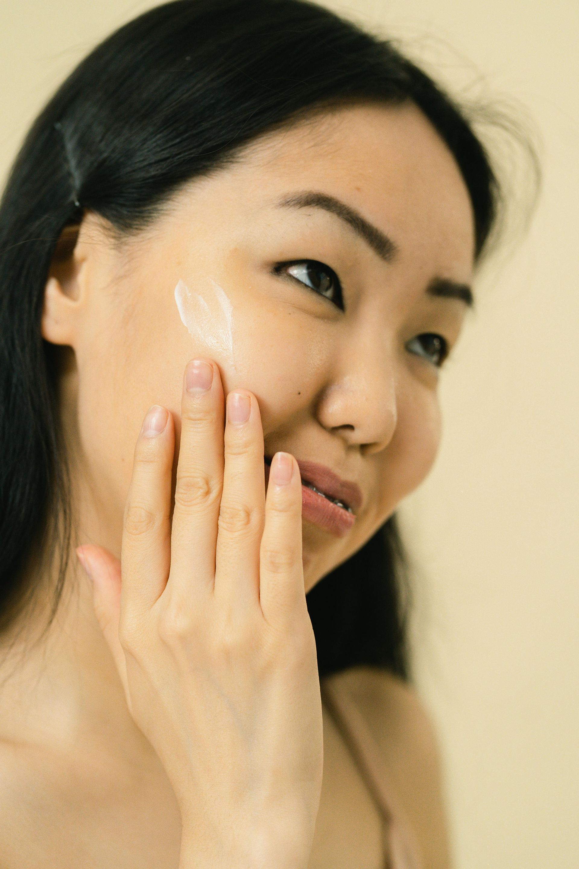 Close-up of a person's face looking up. Brown eyes with mascara, thick, shaped eyebrows, and fair skin.