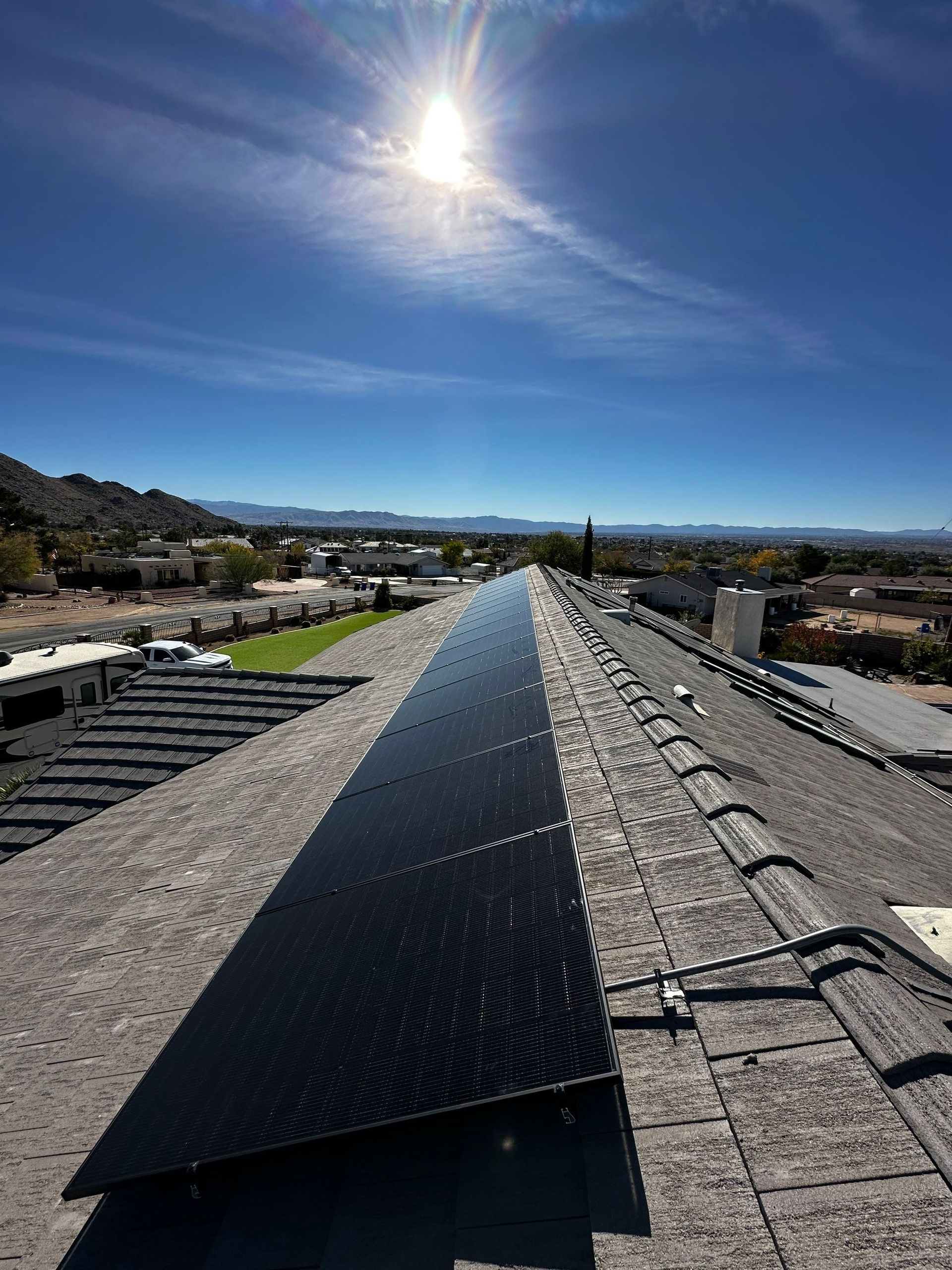 Rooftop solar panels stretching toward the horizon under a bright sun and clear blue sky.