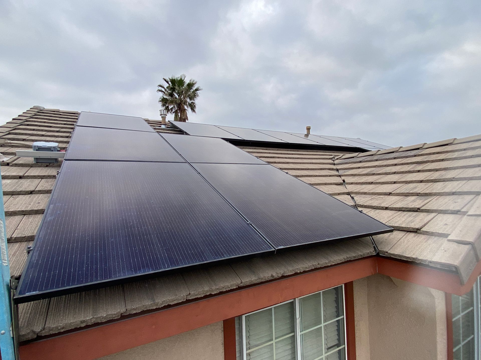 Solar panels installed on a tiled rooftop under a cloudy sky.