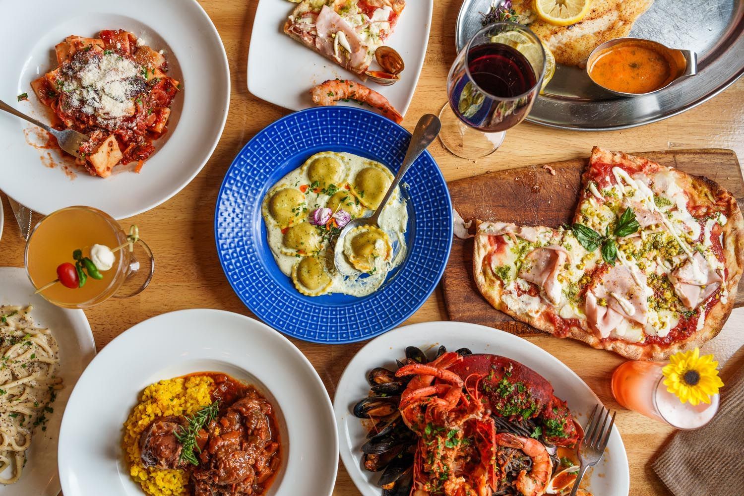 Table of food from Romanissimo including artichoke ravioli and pizza.