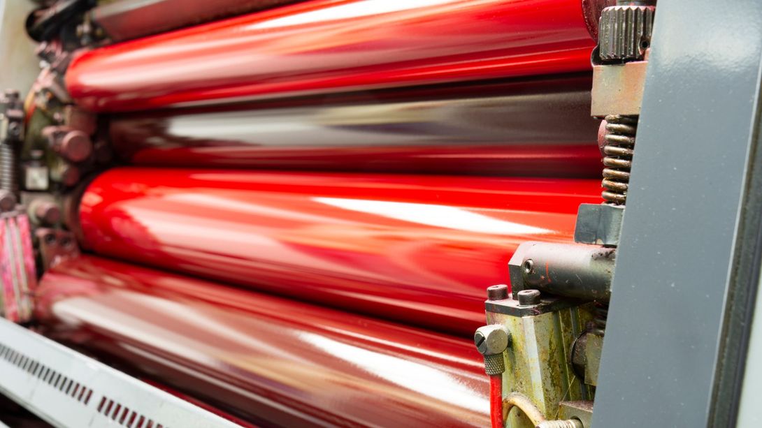 A close up of a printing machine with red rollers.