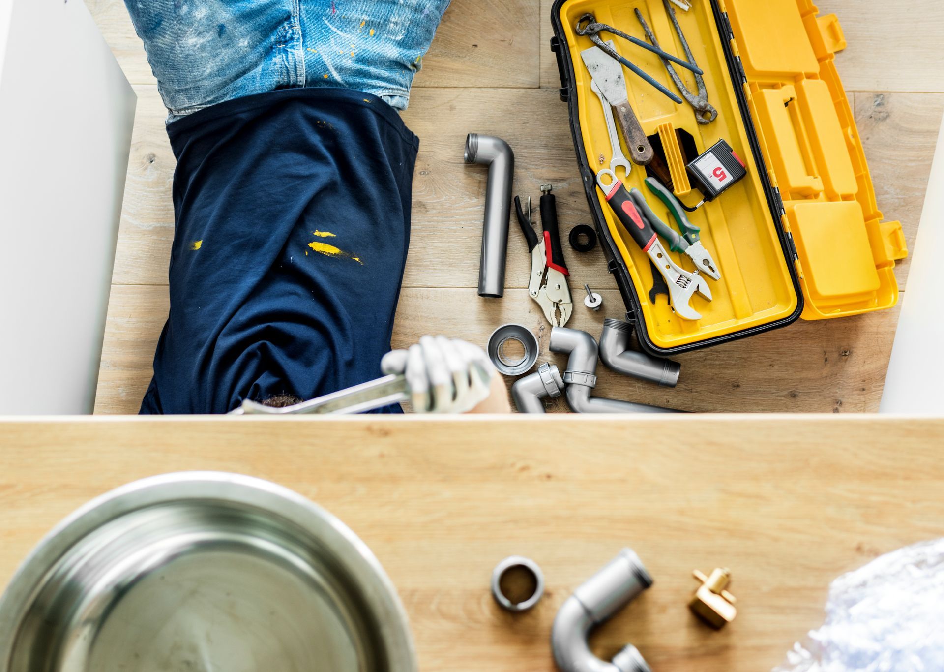 A plumber is working on a sink with tools and a toolbox in Wellington fl