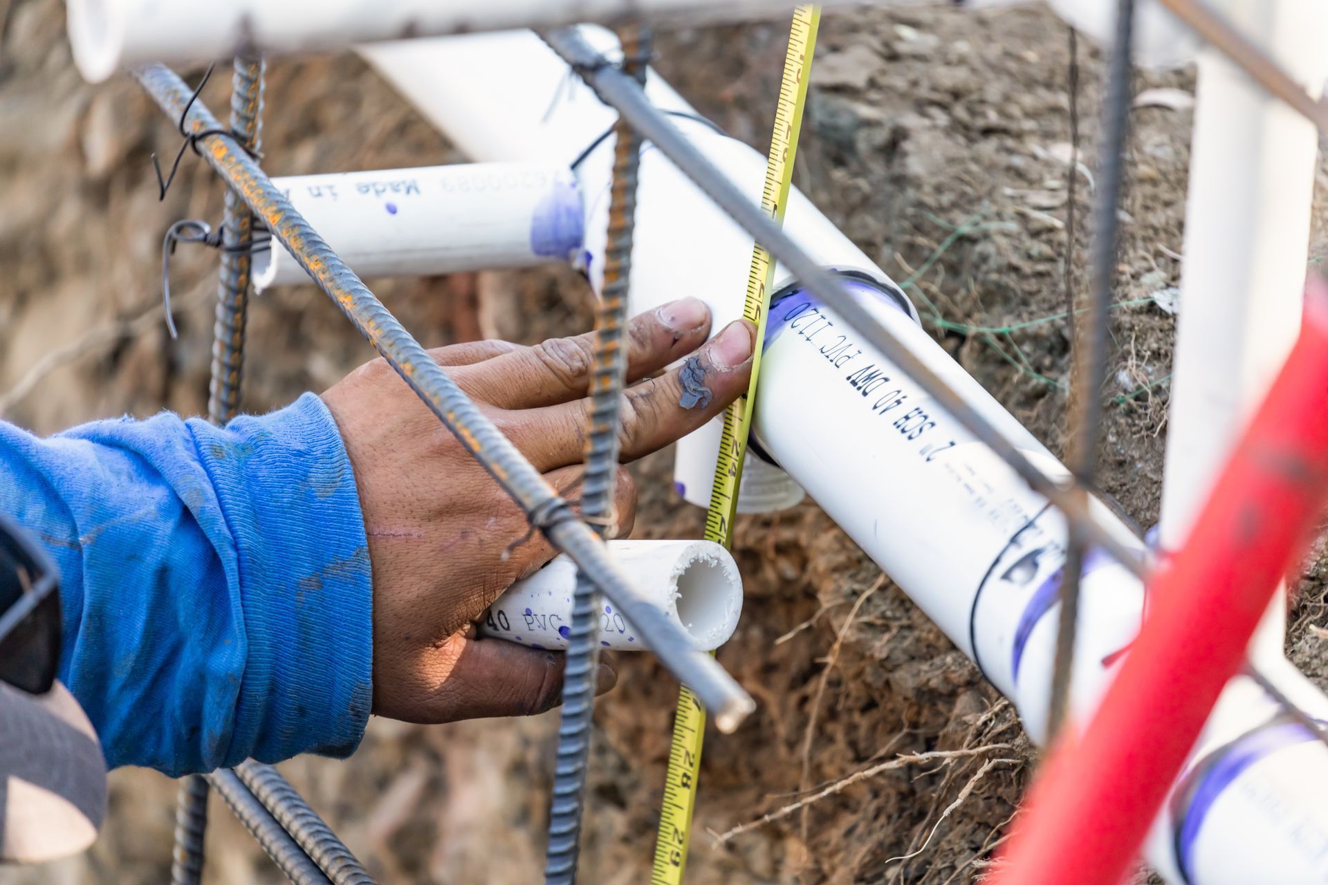 A man is working on a pipe in the dirt for sewage inspection