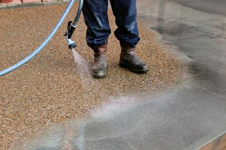 Picture of exposed aggregate concrete being finished off by taking the top layer of concrete off with a hose.