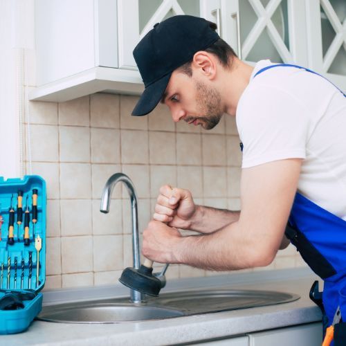 A man is fixing a sink with a plunger