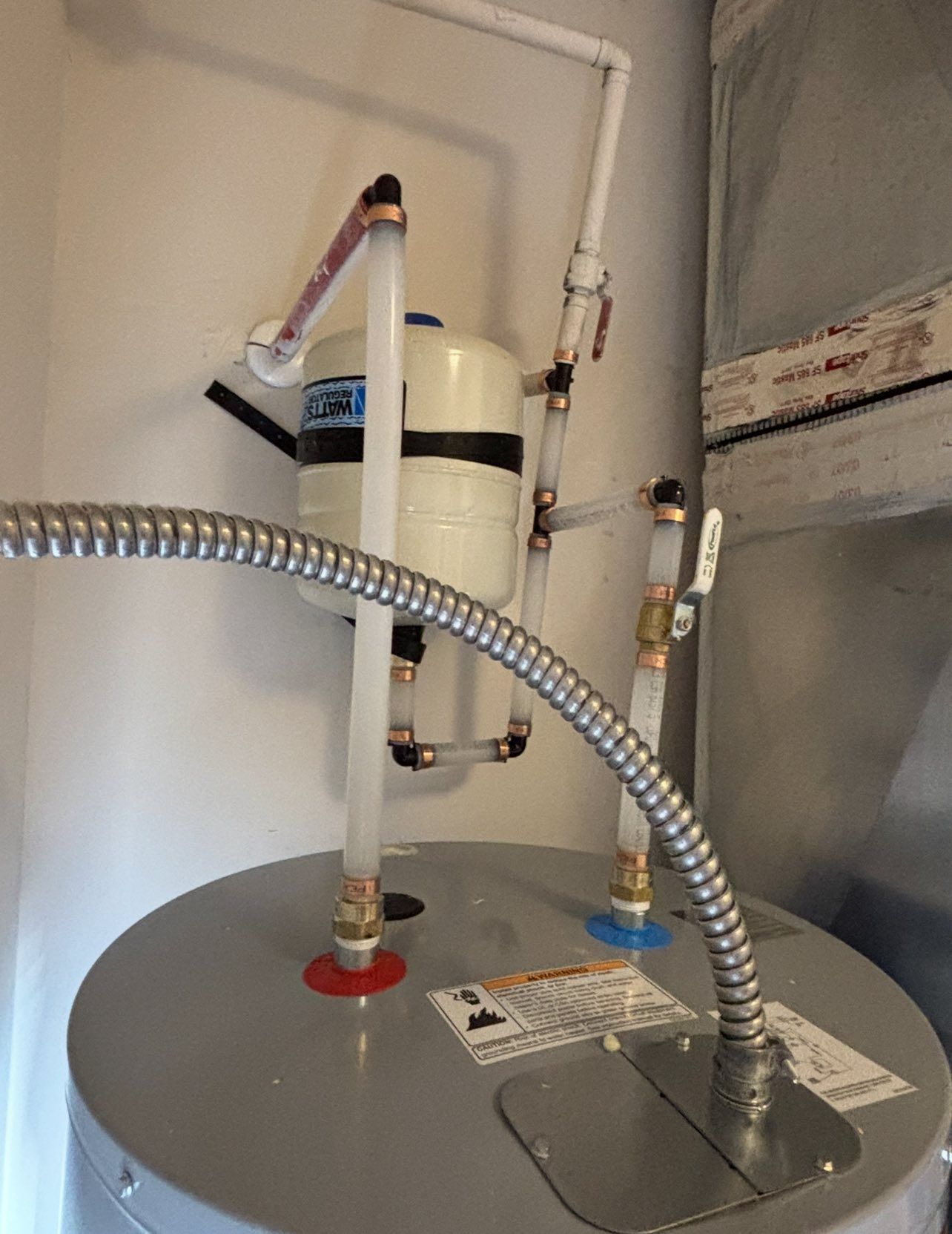 A water heater with a hose attached to it.