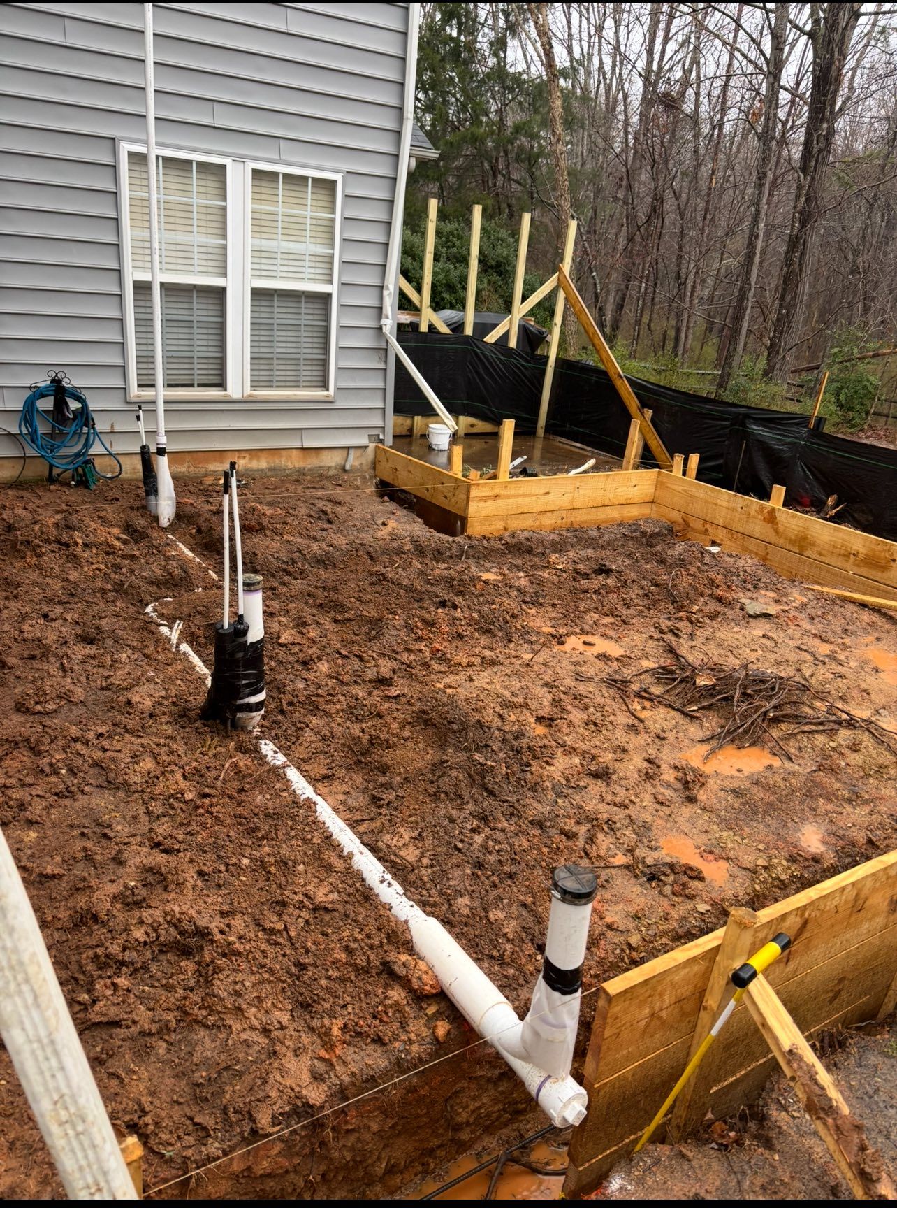 A house with a lot of pipes in the dirt in front of it.