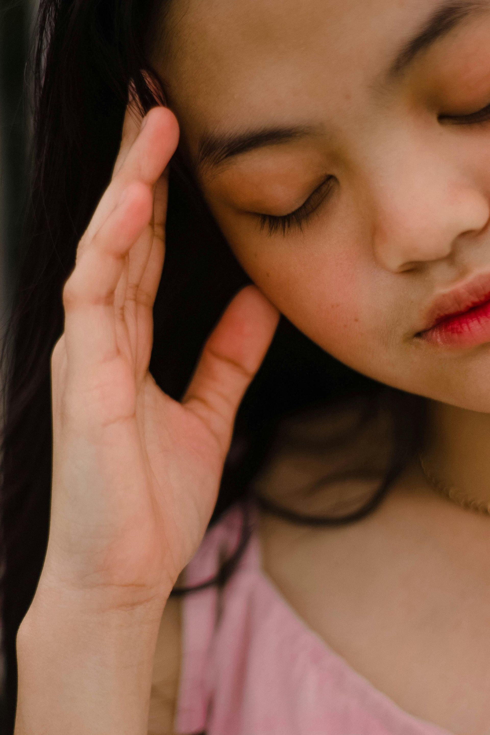 A woman is holding her head with her hand.