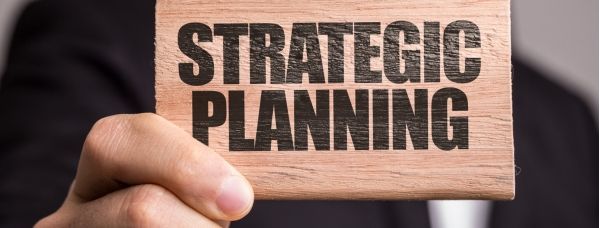 A person holding a wooden block that says strategic planning.