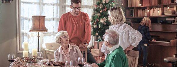 Family having a discussion at the dinner table with a Christmas tree in the background.