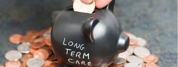 A person is putting a coin into a piggy bank that says long term care