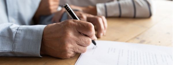 Close up of an elderly man signing a legal document