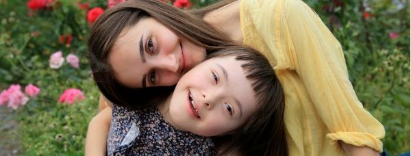 A special needs child and her mom smiling together in the park