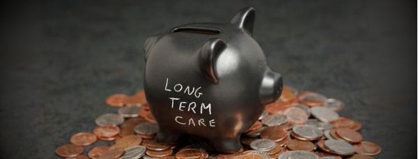 A black piggy bank with the words Long Term Care in white chalk surrounded by coins