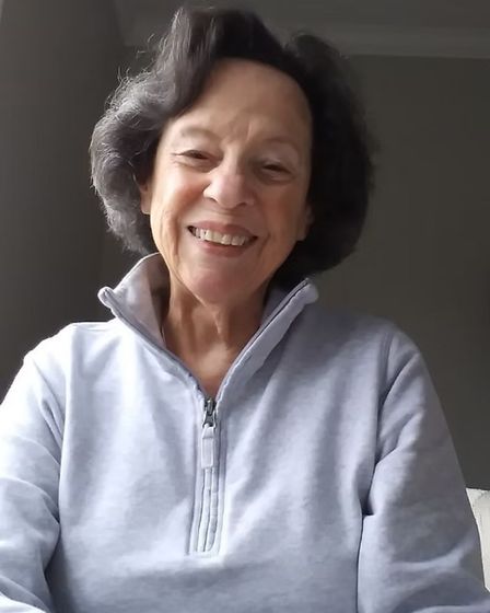 Jane wearing a light blue sweater is smiling for the camera.