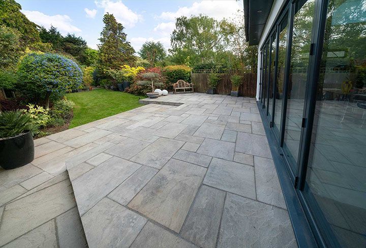 Beautiful sandstone patio with attractive garden and bifold doors.