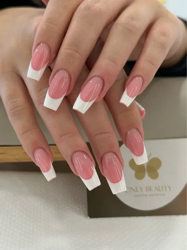 Le unghie di una donna sono dipinte di rosa e bianco con una french manicure