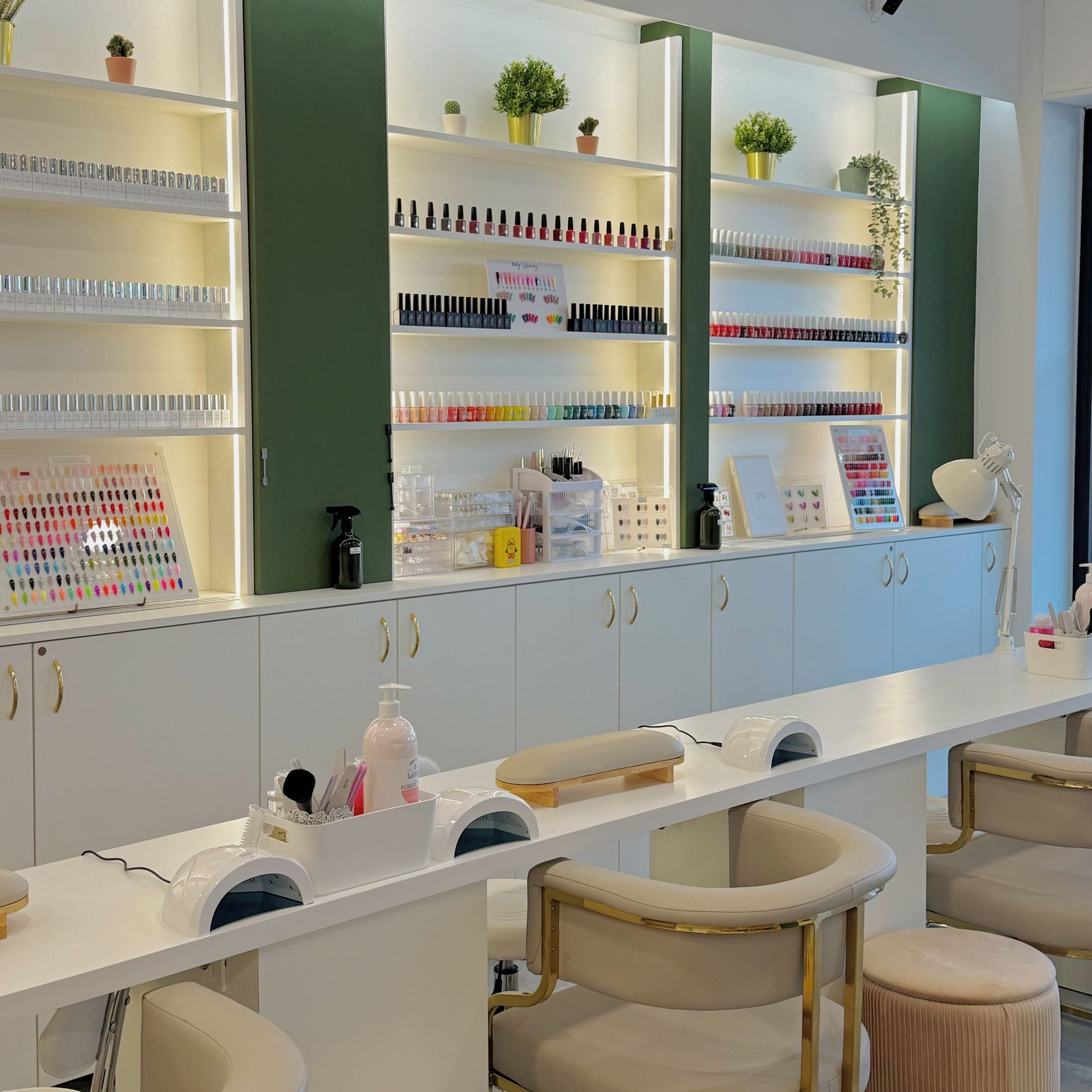 Un salone per unghie con un lungo tavolo, sedie e scaffali pieni di smalti.