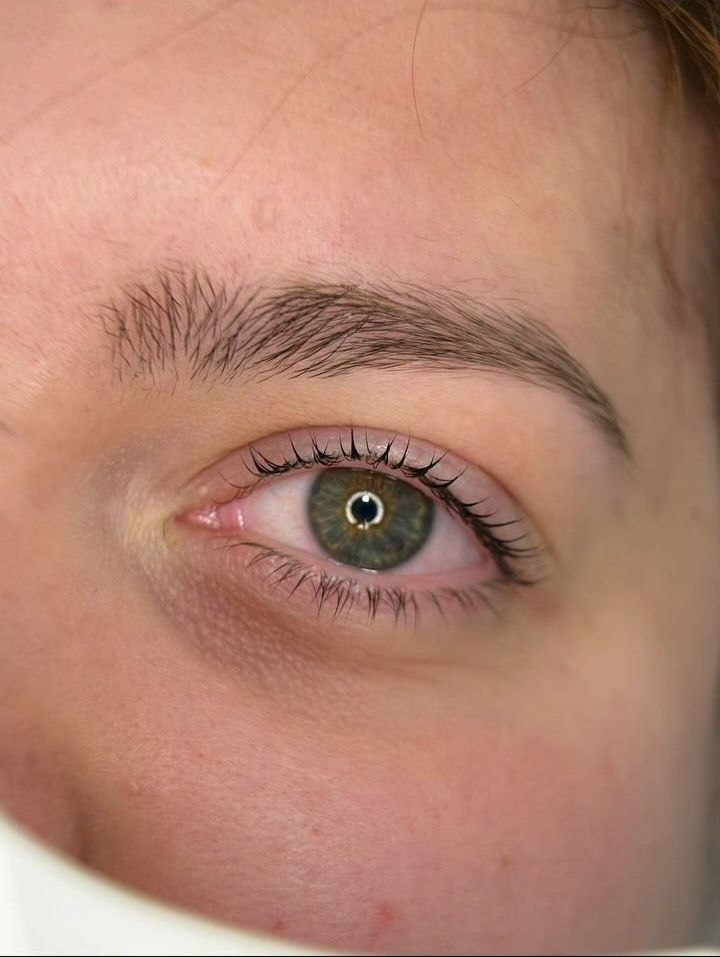 Un primo piano dell'occhio verde e delle sopracciglia di una donna.