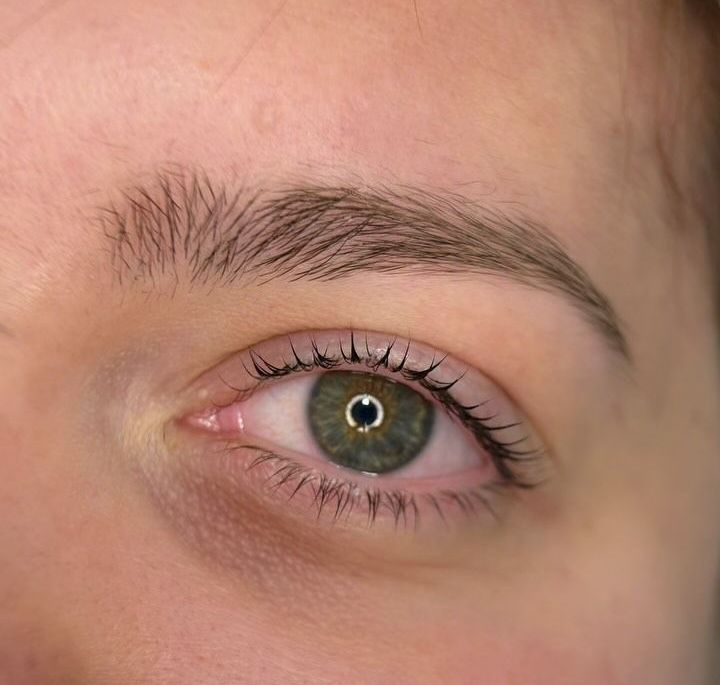 Un primo piano dell'occhio verde di una donna con lunghe ciglia.