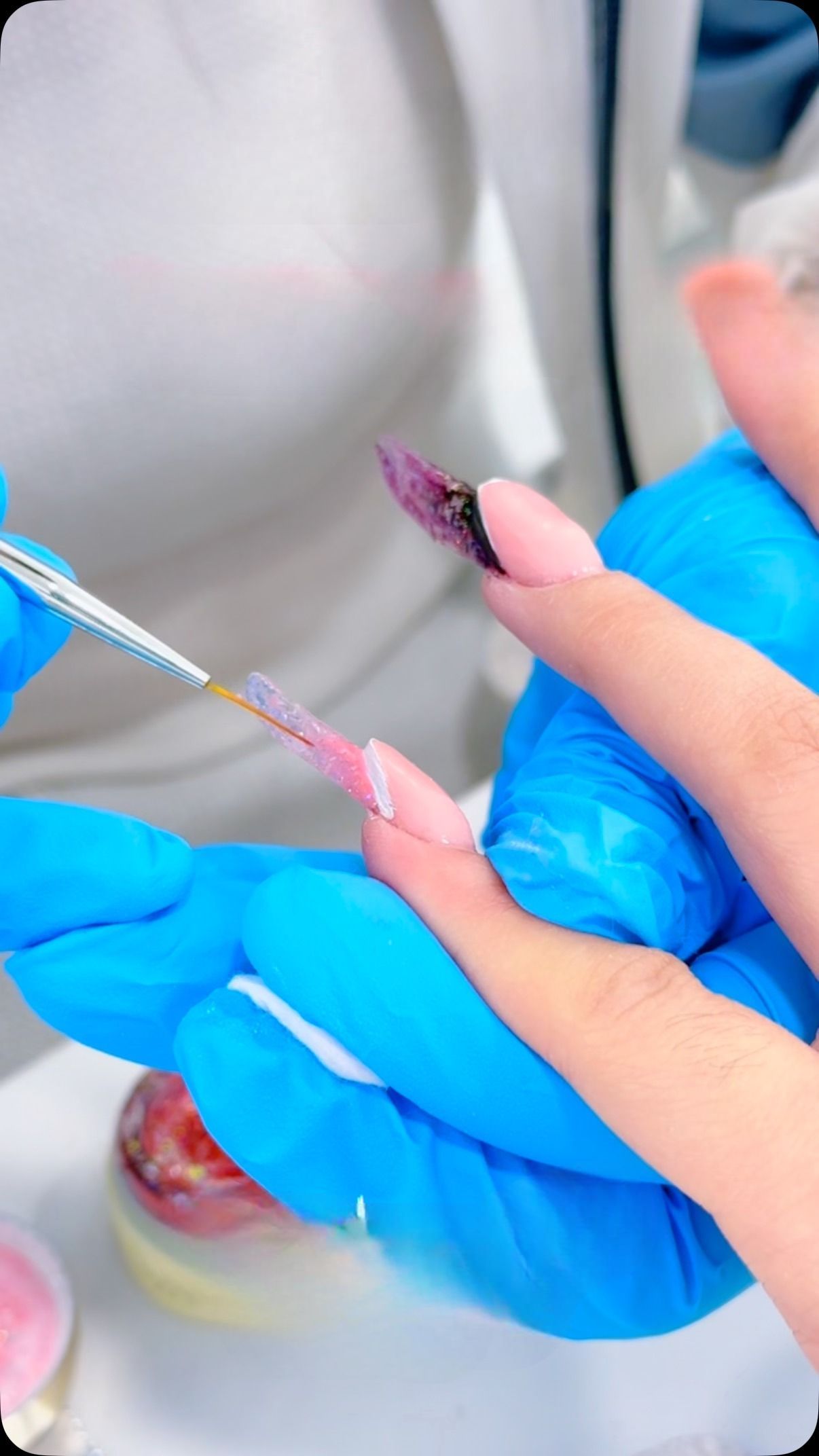 Una donna che indossa guanti blu si sta facendo smaltare le unghie