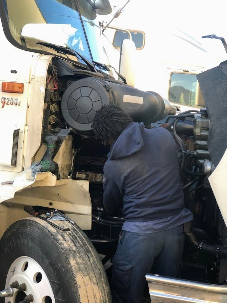 Red, rusty vintage car on a flatbed trailer, wheels secured with straps.
