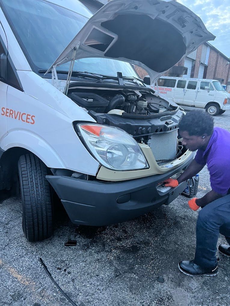 Cars in a mechanic's shop: a blue car on a lift, a silver SUV in the background,